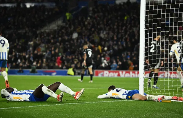 Brighton players lie on the floor after a big missed chance