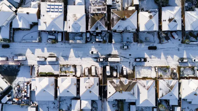 Aerial view of  snow-covered houses linign a snowy road