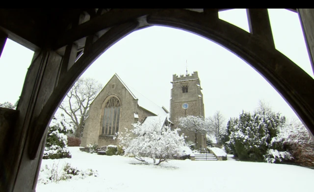 St Oswin's Church in Wylam photographed through an archway and surrounded by snow