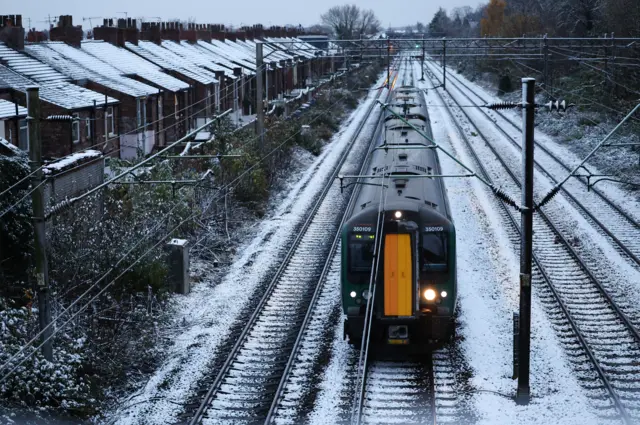 A train passes over snow-covered tracks in Liverpool with terraced houses at the side