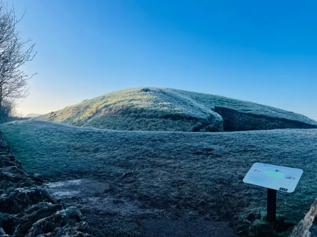 A panoramic shot of Belas Knap dusted with snow