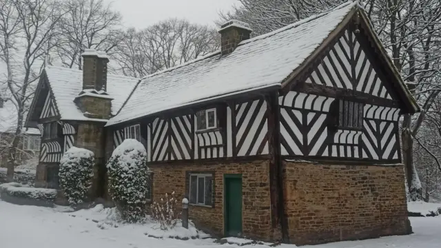 A black a white timber house covered in snow