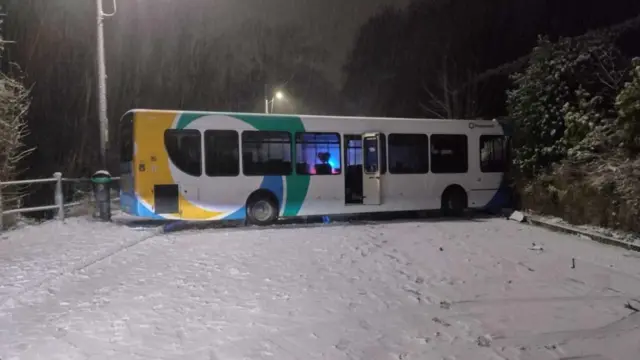 A bus lies across a snowy road