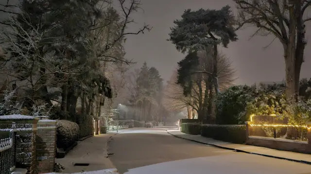 A scene of a residential street covered in snow