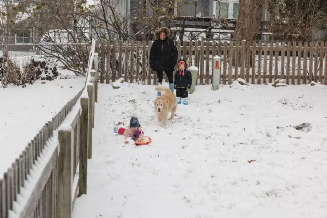 Family and two dogs playing in the snow in their garden in Kansas