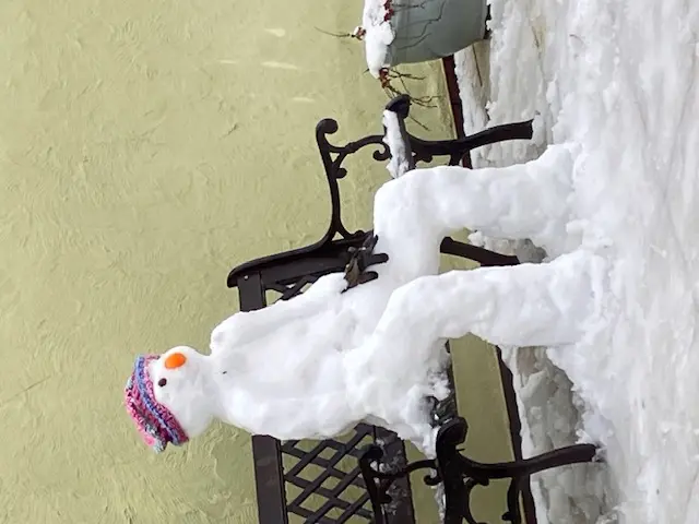 a snowman sitting on a bench wearing a hat