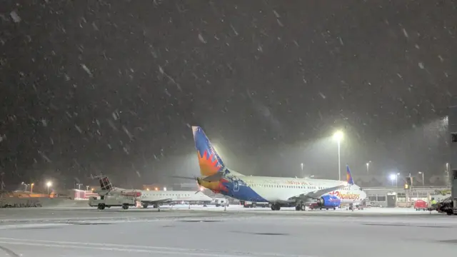 A Jet2Holidays plane at Newcastle Airport with snow falling and on the ground