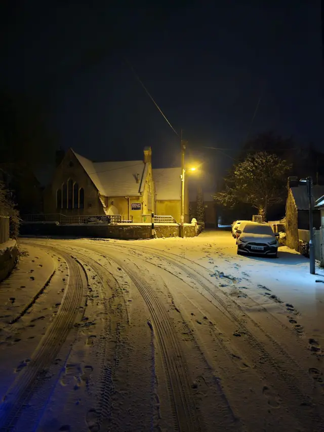 A snowy street in Bradford on Avon, leading to a church in the dark