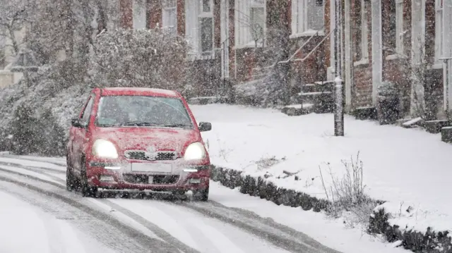 A red car driving on a snowy road