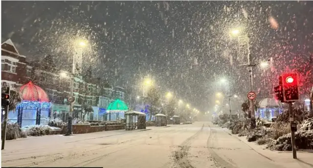 snow falls on street lined with resort hotels