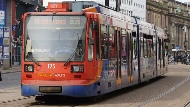 A red and blue tram driving through Sheffield city centre.