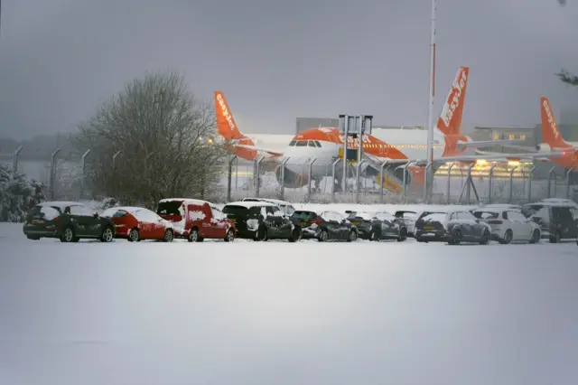 Planes at Liverpool Airport with a snow-covered car park in front of it