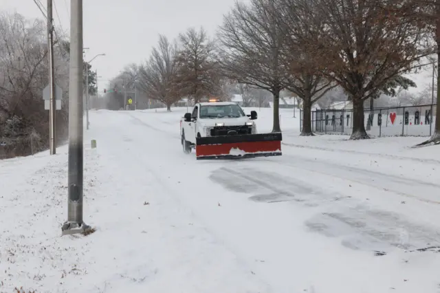 A county truck with a snow plough drives down a road in Kansas