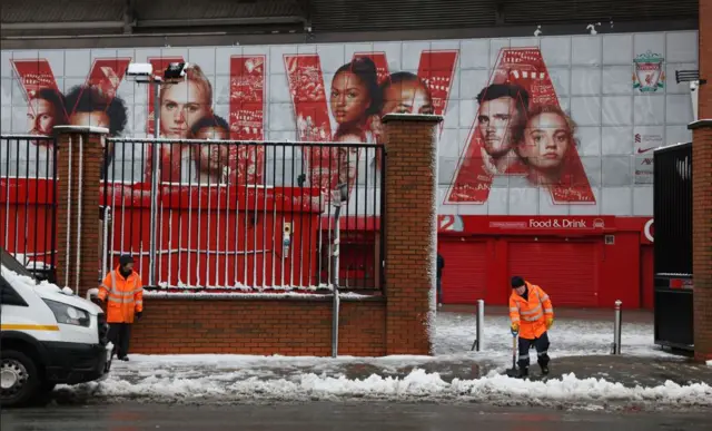 Workers clear snow outside Anfield before the match.