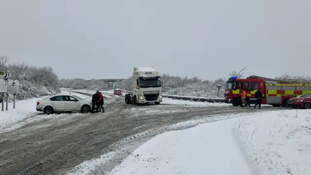 A car, an HGV and a fire engine on a snowy road.