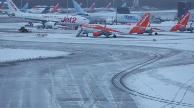 Jet2, EasyJet and Tui planes stand on a runway that appears covered in both snow and ice