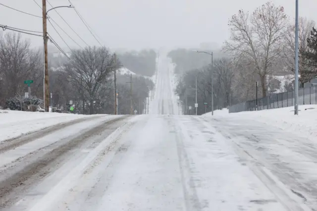 A look down a partially plowed road covered in snow and ice