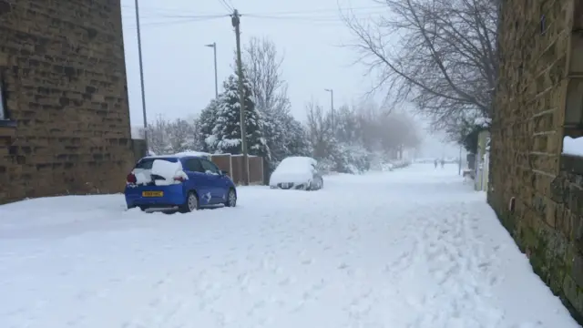 Snow covers the ground and parked cars in West Morley, Yorkshire