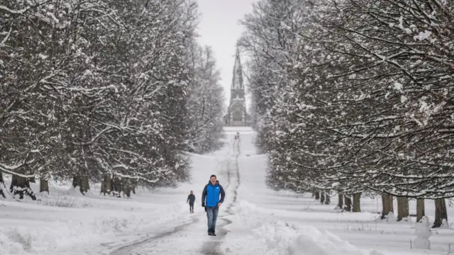 People walking in the snow in Studley Royal park in North Yorkshire. Heavy overnight snow is causing disruption across the UK as the cold start to the new year continues.