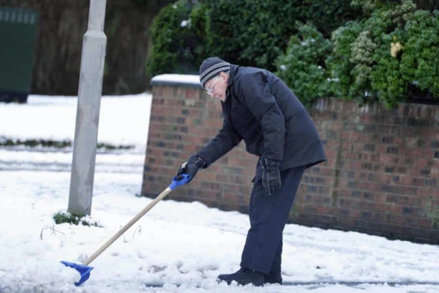 A man pushes snow away with his blue shovel