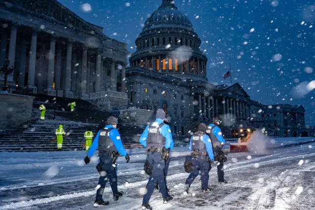 Law enforcement officers walk outside the US Capitol amid heavy snowfall