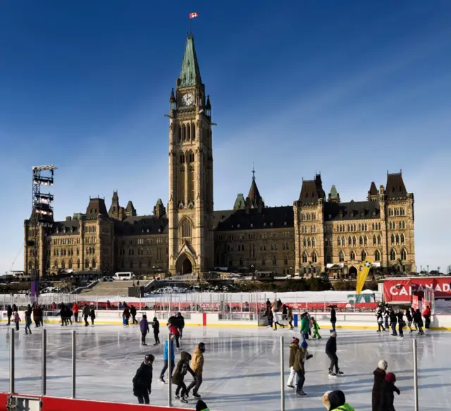 Centre Block Peace Tower in back and ice skaters in front