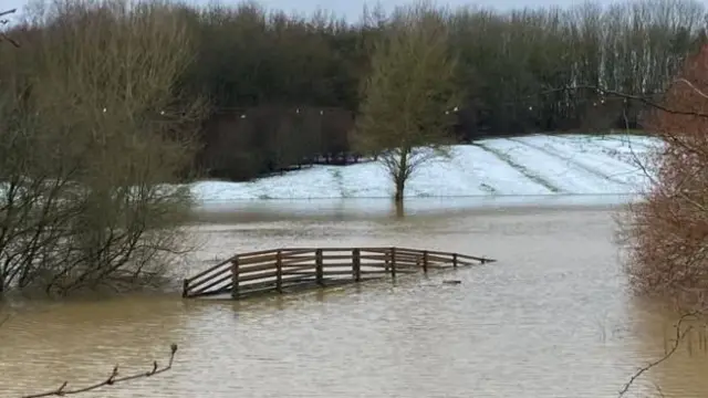 The top of a wooden bridge poking up from flood water