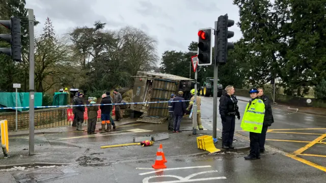 An overturned trailer cordoned off by emergency services