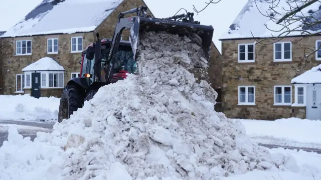 Digger clearing snow in front of houses