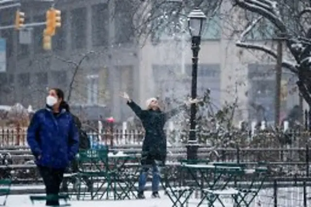 A woman throws snow in the air in Madison Square Park during snowfall in New York City. Photo: 6 January 2025