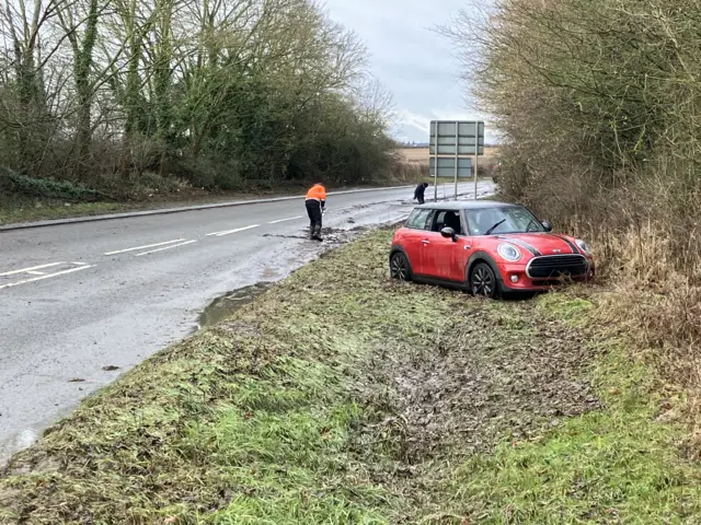 A red car pictured next to a road