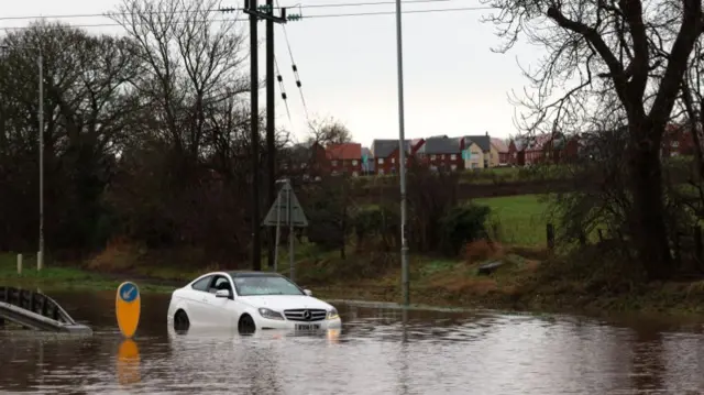 A white car drives through floodwaters