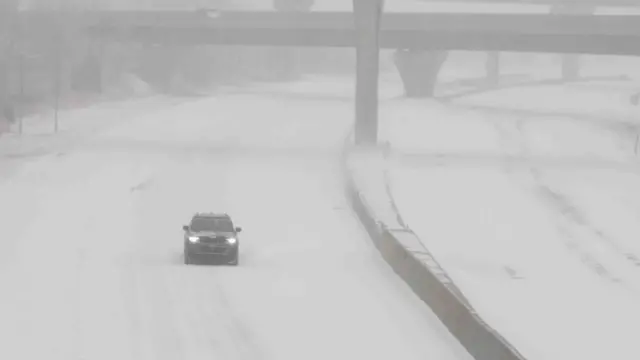 A vehicle travels westbound in blizzard conditions during a winter storm on Interstate 70 in Topeka, Kansas