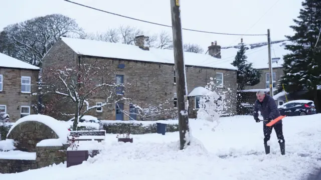 Man shovelling snow outside house