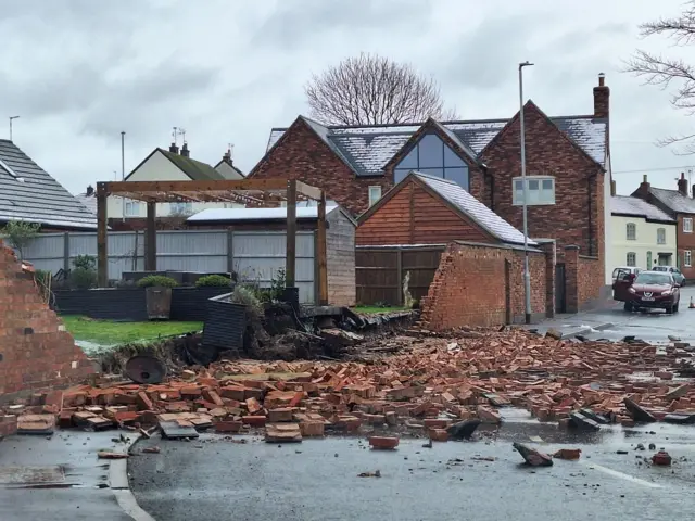 Bricks from a collapsed wall across the road