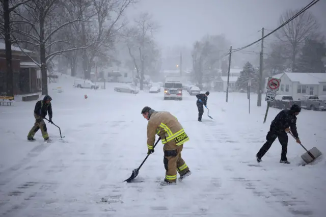 Firefighters shovel snow in front of their station in Kentucky