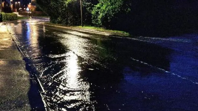 Flood water on a road lit up by a street light