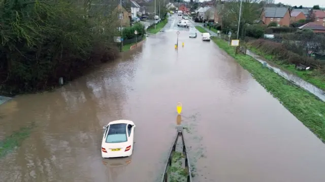 A car in water on a flooded road in Hathern