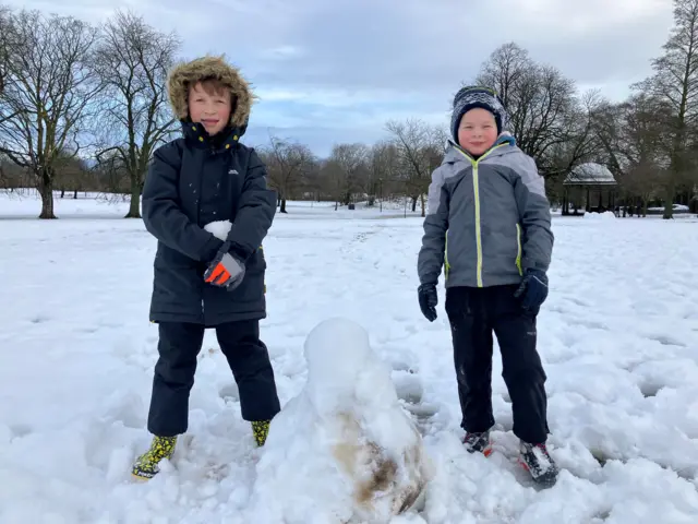 Dante and Freddie - both aged seven years old - stand next to their snowman on The Stray