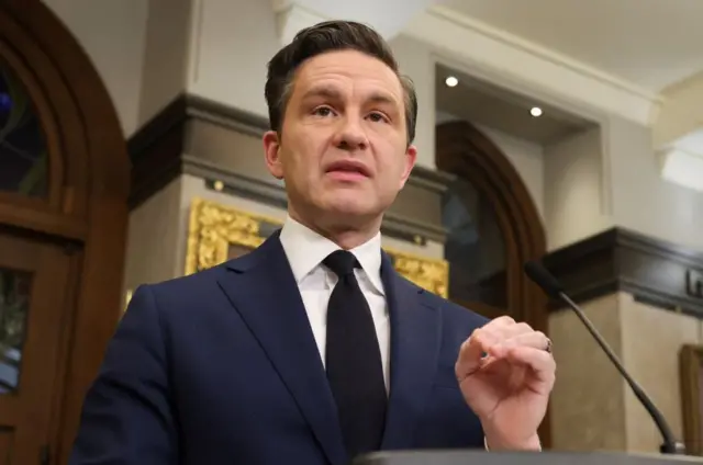 Conservative Party of Canada leader Pierre Poilievre speaks at a lectern with a navy suit and black tie