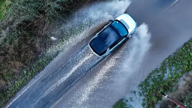 Car driving through road flooded with water