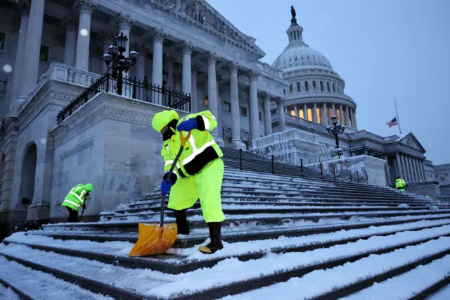 People with shovels clearing snow away from the steps of capitol hill