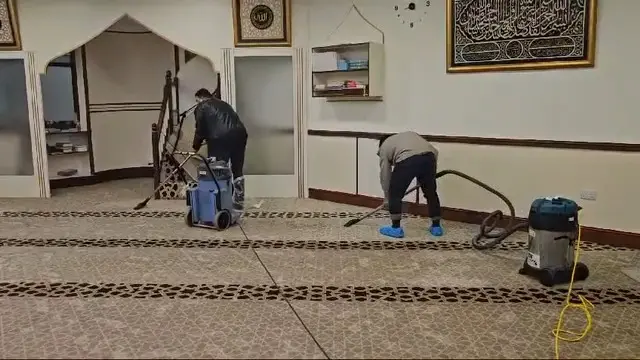 Two men hoovering up inside a sodden mosque