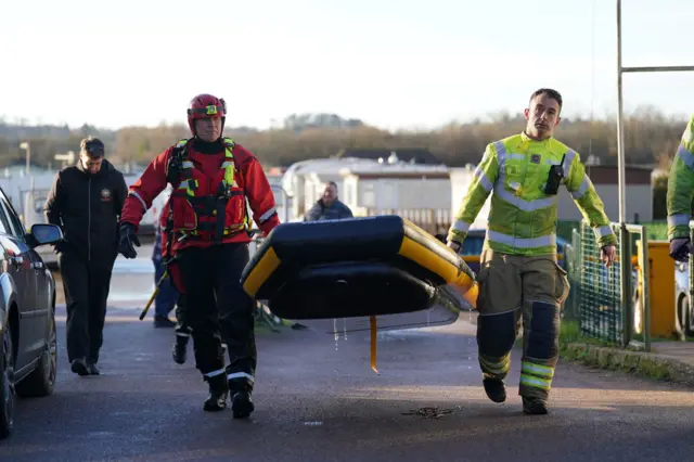 Two rescuers carrying a rubber boat to water