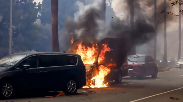 A small van burns after catching fire while the driver was trying to evacuate the Palisades wildfire in Pacific Palisades, California, USA, 07 January 2025. According to the National Weather Service, large portions of the Los Angeles area are under extreme wildfire risk from 07 to 08 January due to high winds and dry conditions. Palisades Wildfire in Los Angeles, California