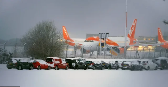 Snow covered cars in front of EasyJet planes