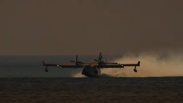 A water bomber aircraft picks up water from the Pacific Ocean, as a wildfire breaks-out near Pacific Palisades on the west side of Los Angeles during a weather driven windstorm in Southern California