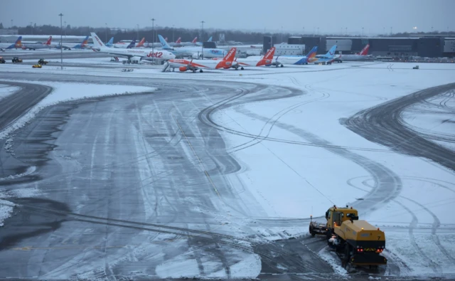 A snow plough waits to help clear snow from around aircraft after overnight snowfall caused the temporary closure of Manchester Airpor