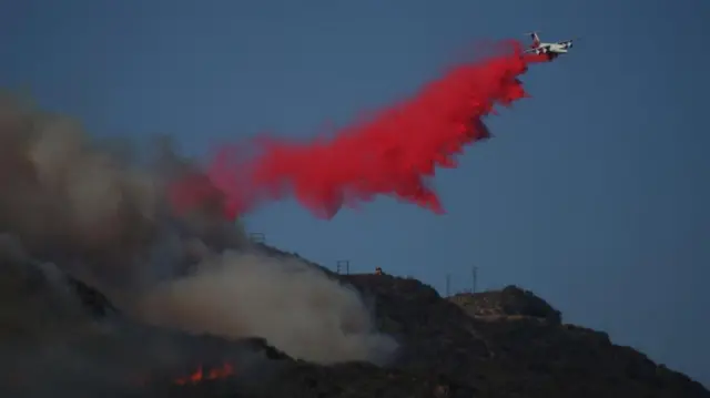 A plane drops fire retardant on a fire