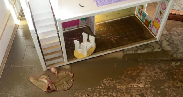 A dolls house covered in muddy water